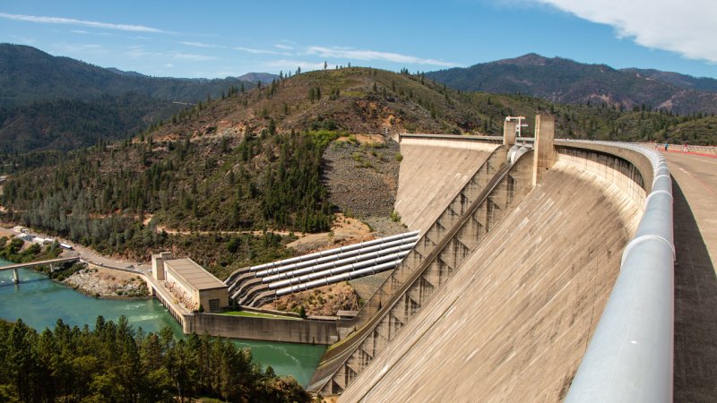 The curved concrete gravity dam of Shasta on the Sacramento river in California, USA. It is 1,000 m long and at its base 165 m thick. (Source: © Cayetano / stock.adobe.com)