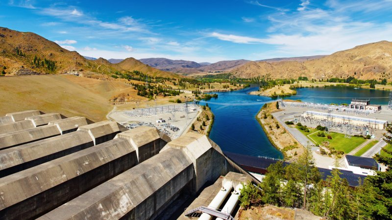 Sizeable concrete penstocks are used to feed water to the powerhouse of the Benmore power plant, New Zealand. Further away we can see transformers and power lines. (Source: © Dmitry Pichugin / stock.adobe.com)
