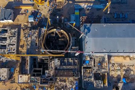Aerial view of a nuclear power plant under construction showing the circular reinforced concrete containment building that will house the reactor and primary circuit systems. (Source: © hlxandr / stock.adobe.com)