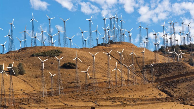 A wind farm with a large number of wind turbines situated on a mountain ridge with favourable wind conditions. (Source: © BVDC / stock.adobe.com)
