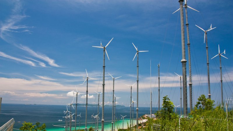 Small wind turbines installed on a hillside overlooking the coast of Ko Lan, near Pattaya, Thailand. (Source: © Surachai / stock.adobe.com)